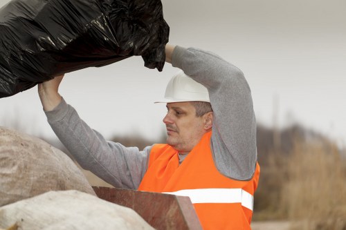 Workers positioning a skip on a roadside with safety cones